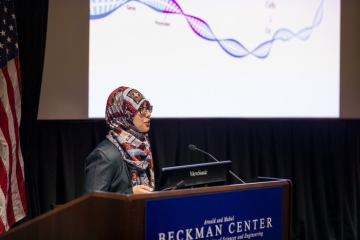 student giving a presentation in front of a screen displaying DNA